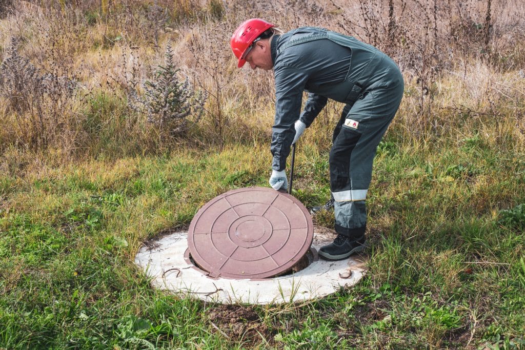 worker lifts manhole cover